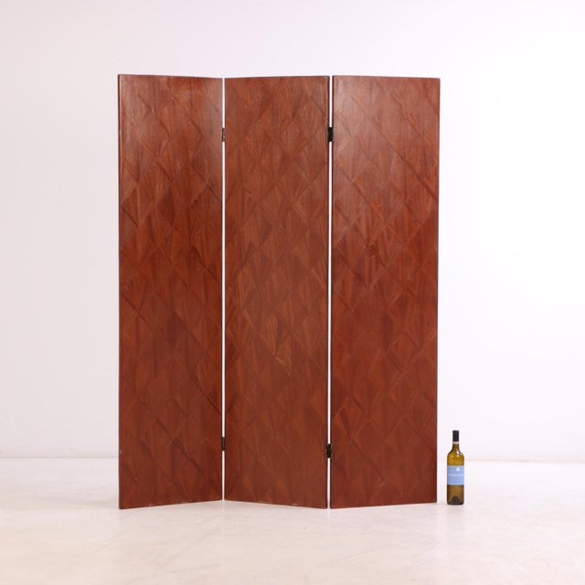 A sophisticated three-panel folding screen featuring mahogany and intricately applied straw marquetry veneer, in the...