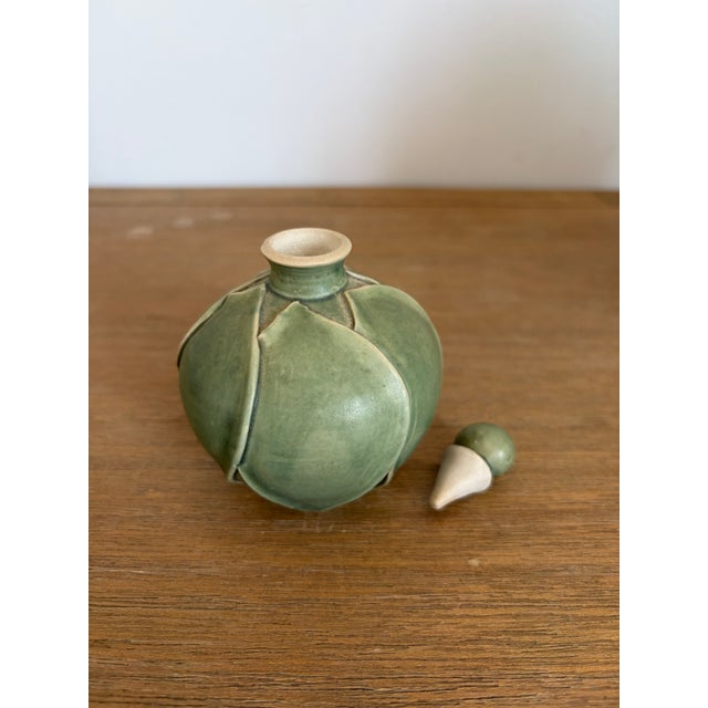 A charming handcrafted studio pottery perfume bottle with a delicate green leaf motif and soft satin glaze. The piece has...