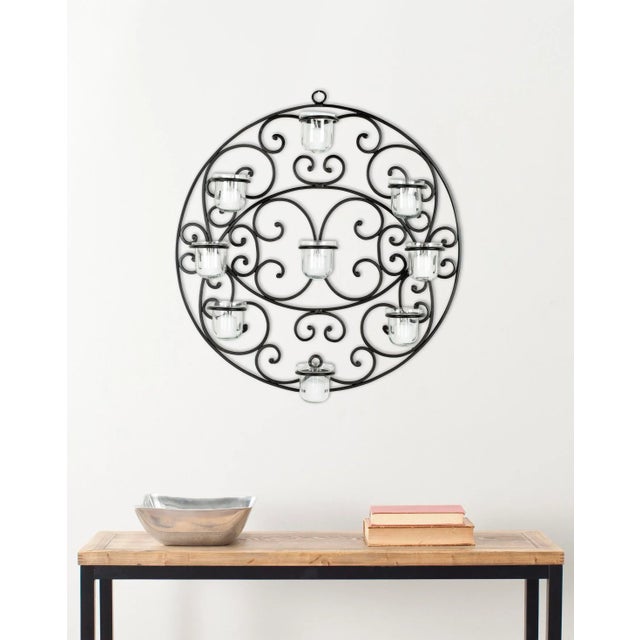 Scrolls of varying size are set in a round frame in this tea light wall sconce. The the design, with nine glass cups,...
