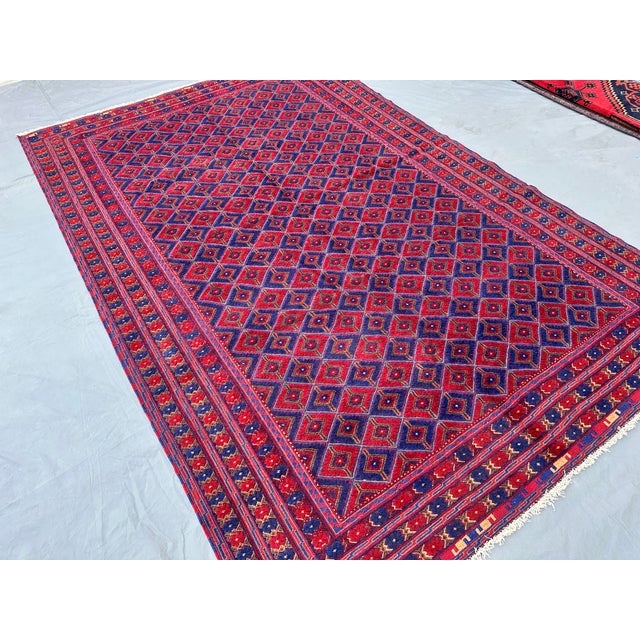 This eye-catching Andkhoy rug features a dense diamond trellis alternating between deep crimson and royal blue...