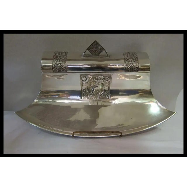 A beautiful circa 1925 Art Deco inkwell designed in polished pewter & featuring a center panel of cherubs at play. A cover...