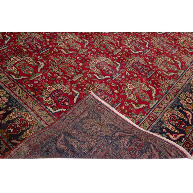 Beautiful Antique Persian distressed hand-knotted wool rug with a red field. This piece has blue, green, and beige accents...