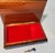 A nice wooden jewelry box with marquetry woodwork and a red velvet compartment inside. A sticker on the bottom states that...