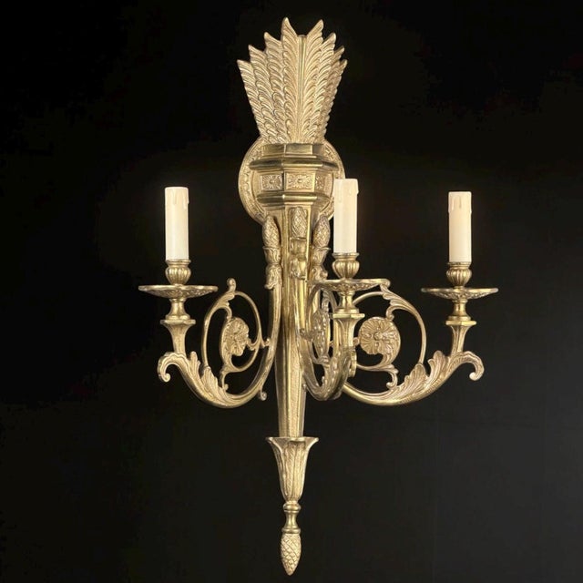 An impressive and richly decorative wall sconce in the French neoclassical style, featuring an elegant three-arm design....