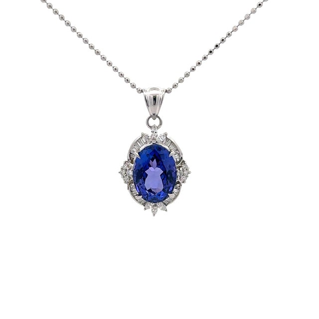 A captivating pendant necklace showcasing a 9.73-carat oval tanzanite with a deep blue hue. The tanzanite is beautifully...