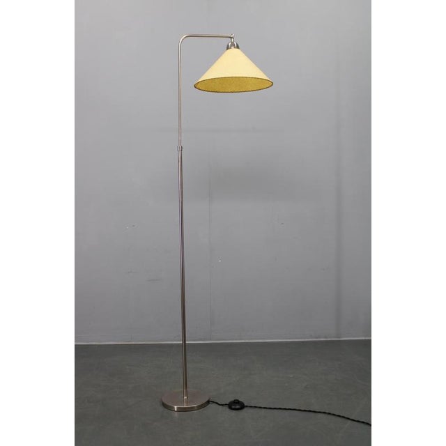An elegant adjustable Art Deco floor lamp produced in Czechoslovakia during the 1930s. The lamp features a slender nickel-...