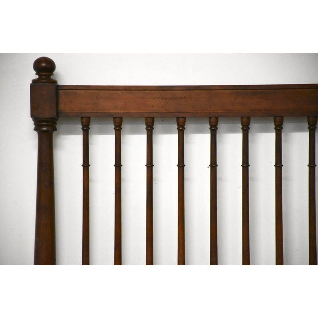 A distressed solid maple queen size bed in a deep cherry stain with vertical props along the headboard and footboard....