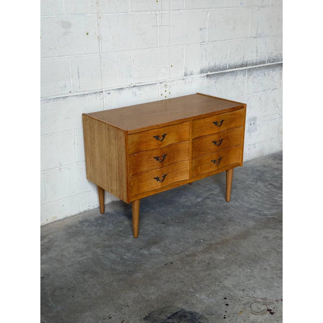 This stunning oak dresser features six spacious drawers and clean architectural lines. Elevated on slender tapered legs,...