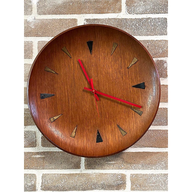 Vintage wall clock from the 1960s in Mid-Century Modern style, featuring a refined circular teak wood case in a warm hue...