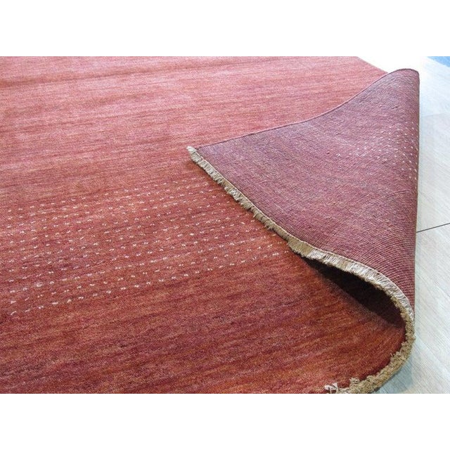 This hand knotted pile rug features a primary color palette of coral, salmon, and pink. Crafted from wool, this floor...