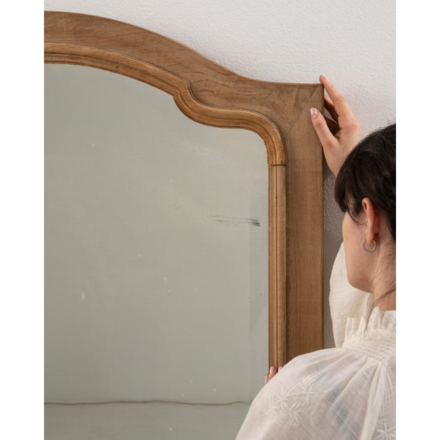 A circa 1900 French wall mirror in the Louis Philippe style, featuring a vertically oriented frame with softly rounded...