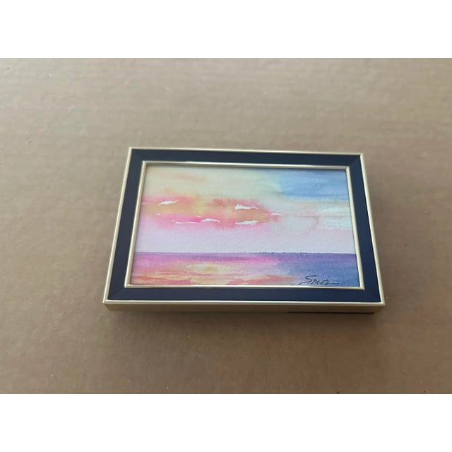 This vibrant miniature watercolor features a dreamy sunset over a calm sea in pink, gold, and blue hues. Nicely framed in...