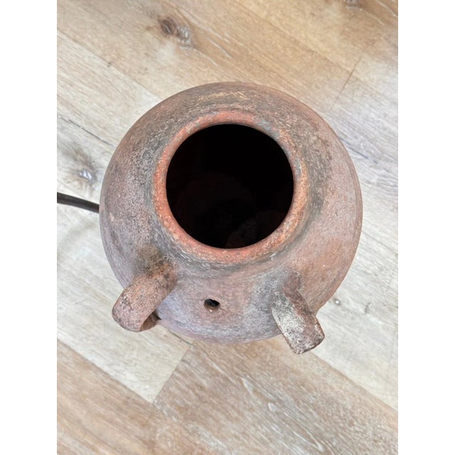A hand-thrown terracotta olive jar with loop handles and weathered patina, likely 19th century Mediterranean. Elevated on...