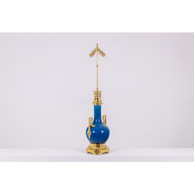 Louis xvi style lamp in blue porcelain and gilded bronze, with its handles ending in leaves, the top of the frame...