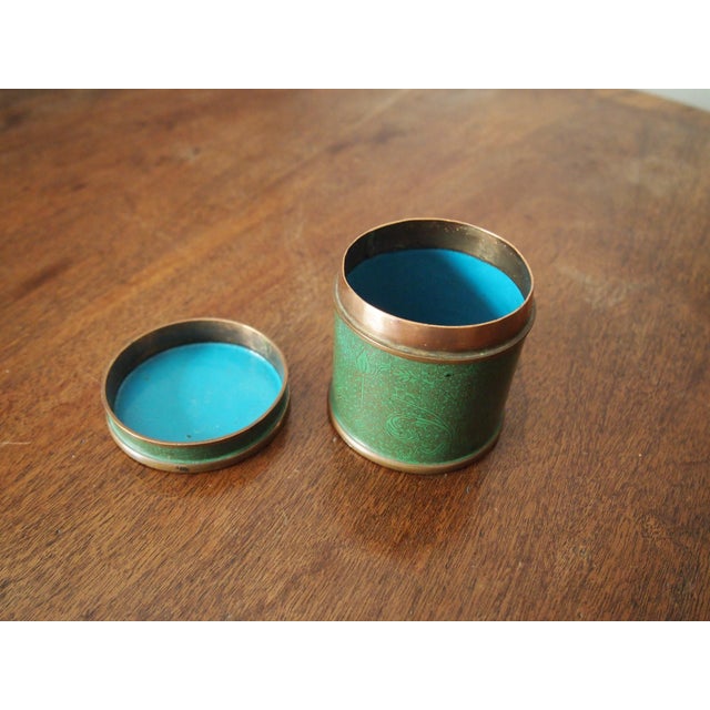 Green Chinese Cloisonné cylindrical box with subtle swirling copper decorations and a blue interior and underside.