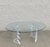 unique coffee table features a sculptural lucite base with a wavy design, supporting a sleek oval glass top