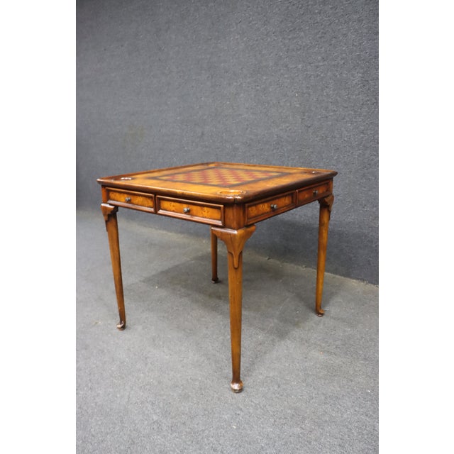 Theodore Alexander walnut game table featuring a square checkerboard playing surface in red and golden yellow, framed by...