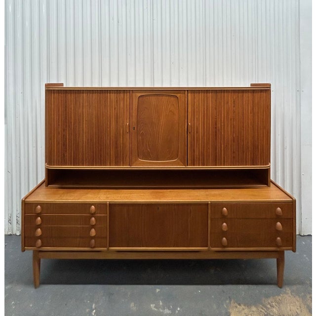 Very unusual mid century modern Danish Teak credenza with hutch top. Tambour sliding doors and mini bar in the center on...