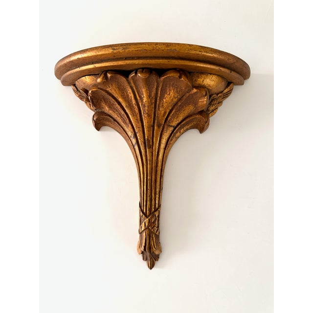Mid Century Hollywood Regency gold wall shelves. The shafts feature elegant fluting leaves below a demilune shelf. Great...