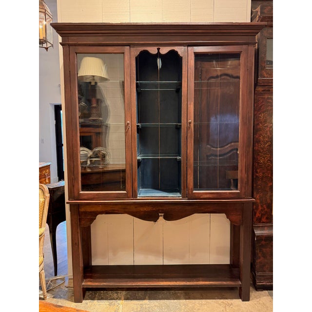 19th century cabinet on stand with a stepped cornice over two glazed doors flanking an open center section with a shaped...