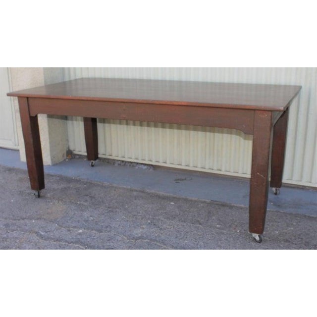 This large work table or farm table like table with original casters / wheels. The legs are tapered and the table is in...