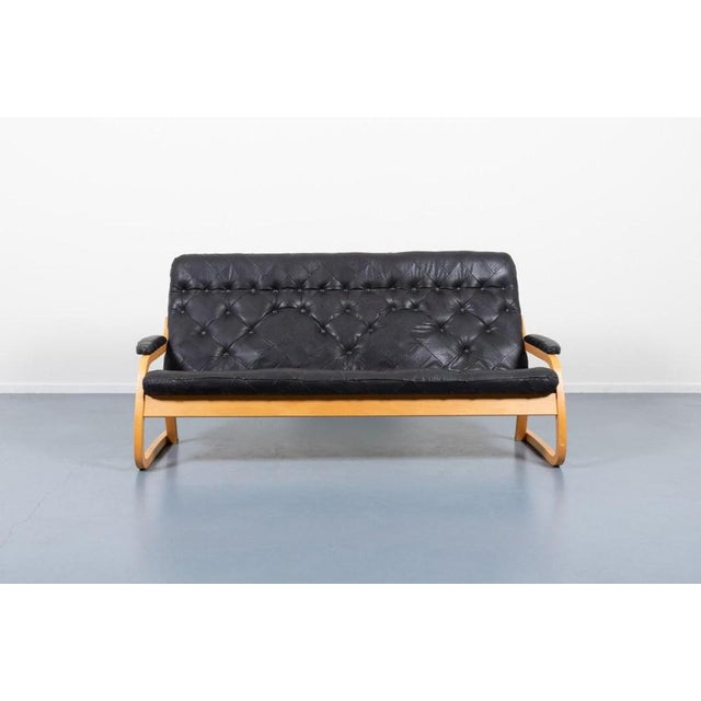 1970s Vintage Sculptural sofa in patinated black patchwork leather on bended beech frame. Produced in Denmark. Condition...