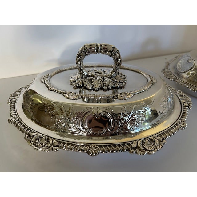 English Silver plate pair of oval entrée dishes with detachable top handles and exterior floral and shell design details....