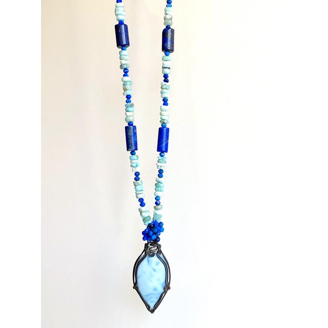 A striking one-of-a-kind artisan necklace composed of genuine Larimar and richly saturated Lapis Lazuli gemstones,...