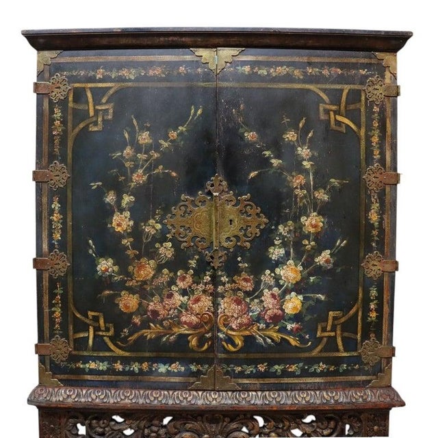 The cabinet rests on a finely carved wooden stand, which exhibits traditional Chinese craftsmanship with openwork carvings...
