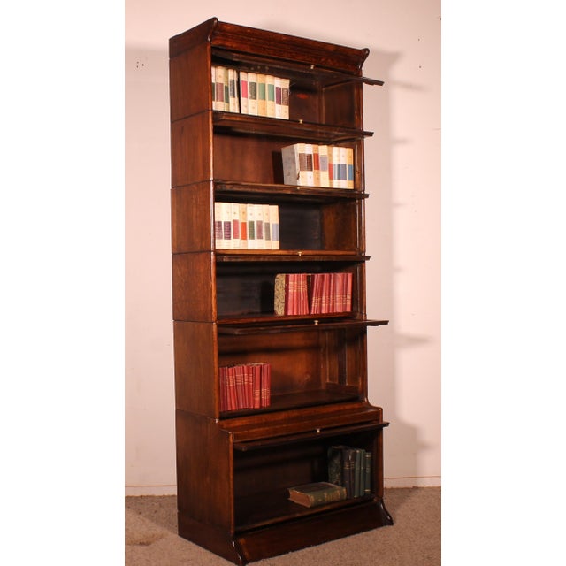 Elegant oak stacking bookcase from late 19th/early 20th century England, featuring six sections and a projecting shelf....