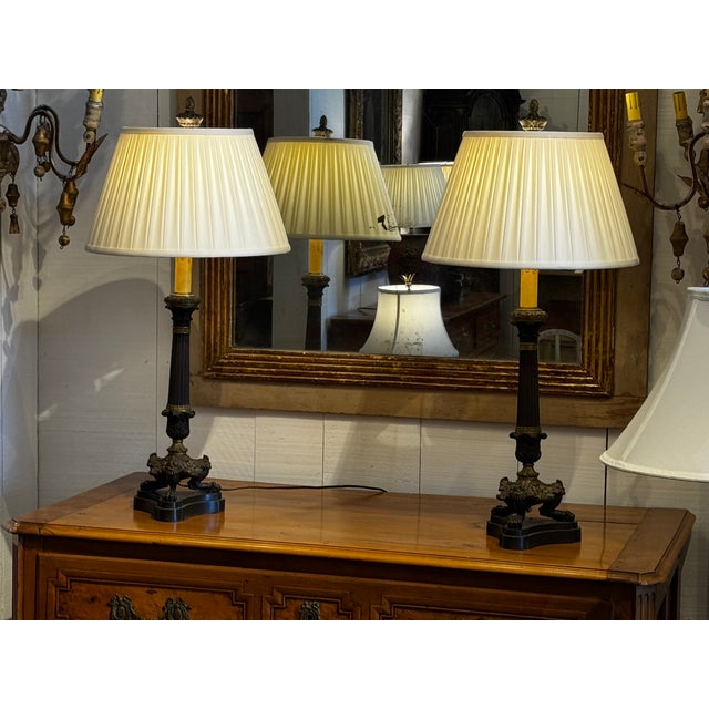 A pair of French Empire Style bronze lamps with fluted columns rising from sculptural bases formed by crouching lion...