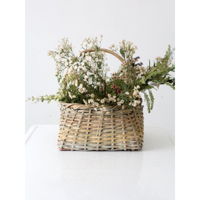 This vintage handwoven basket features a charming square base, a gently curved handle, and a beautiful creamy-white...