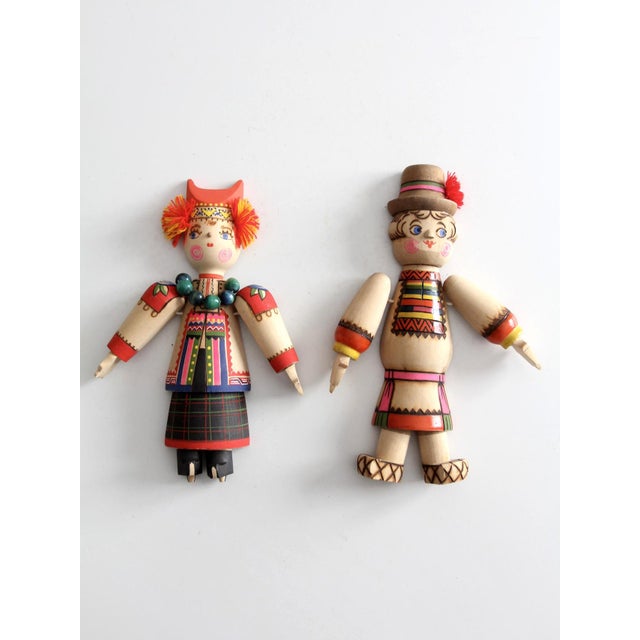 A pair of mid century scandinavian folk art wall hangings featuring articulated wooden limbs and hand-painted traditional...
