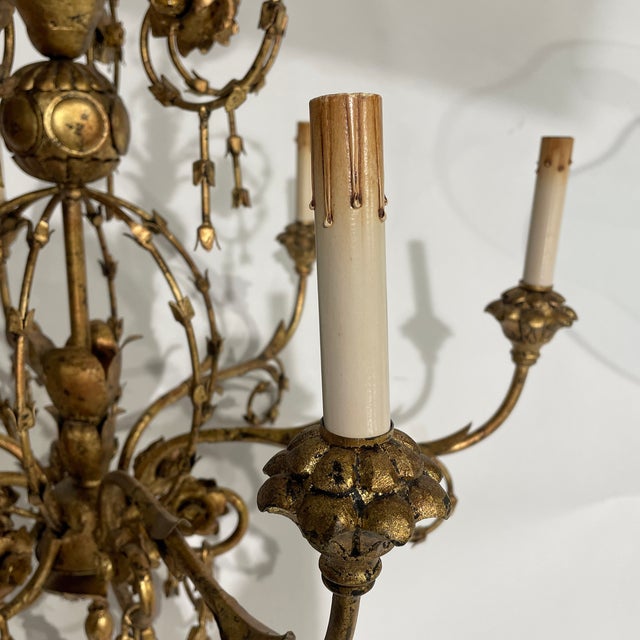 Elegant vintage chandelier featuring graceful floral motif and six candle style lights finished in antique gold color.