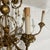 Elegant vintage chandelier featuring graceful floral motif and six candle style lights finished in antique gold color.