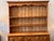 A warm and characterful English pine dresser in two parts. The upper rack has open shelves beneath a scalloped apron and a...