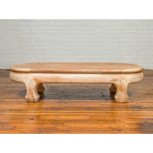 A vintage Thai teak wood oval top coffee table from the mid-20th century, with whitewash finish and chow legs. Crafted in...