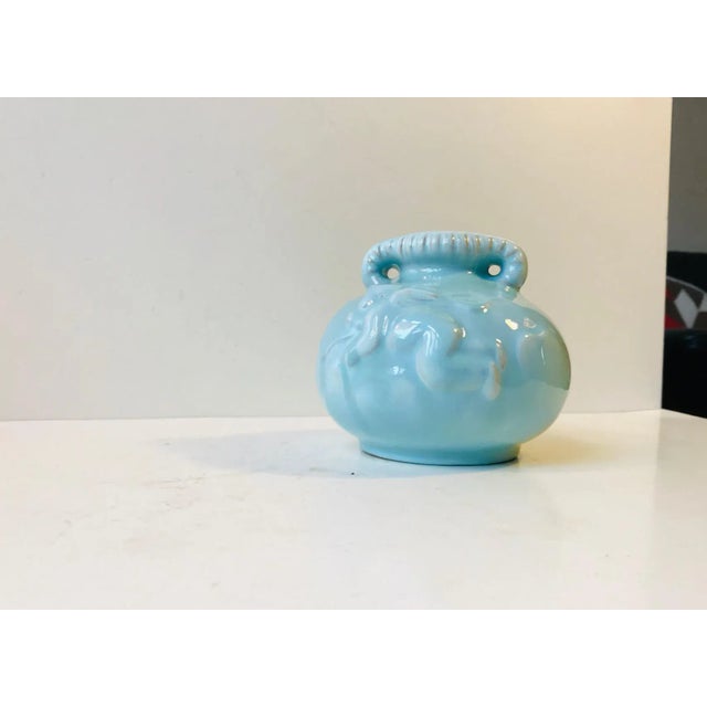 A celodan glazed handled vase with a Cherub in relief. It is stamped and numbered by the maker to the base.