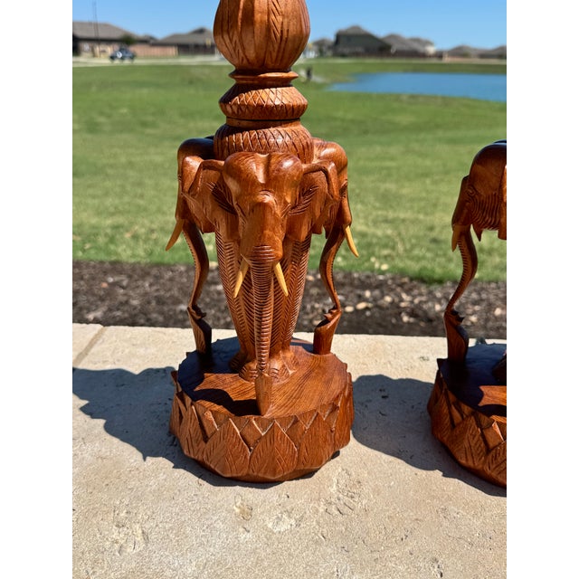 C. 1960s pair of carved teak elephant and lotus form table lamps. Both in excellent condition. One lamp has lost two...