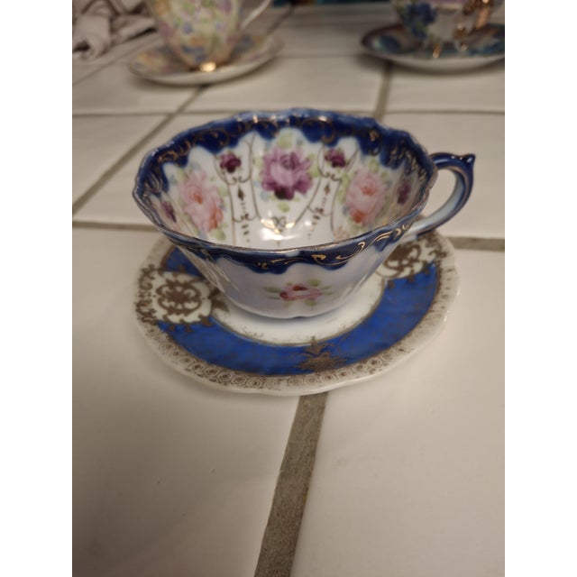 Description: ​Antique-style porcelain teacup and saucer set featuring rich cobalt blue bands adorned with intricate, hand-...