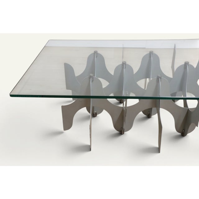 Sculptural coffee table with a minimalist 80s design. Structure in superimposed metal slats and thick transparent glass...