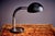 This vintage desk lamp, designed by the renowned Hillebrand Lighting in the 1970s, features a black base with a silver...