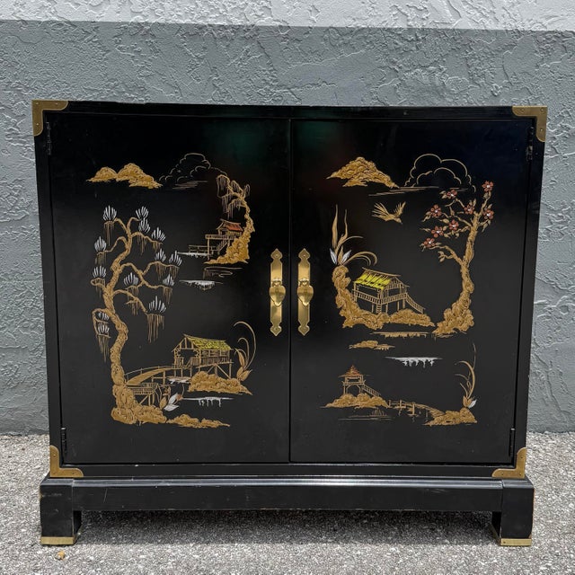A striking vintage Chinoiserie sideboard featuring a glossy black lacquer finish adorned with hand-painted Asian landscape...