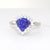 This elegant ring is crafted in 18K white gold. It features a striking trillion-cut tanzanite, surrounded by a halo of...