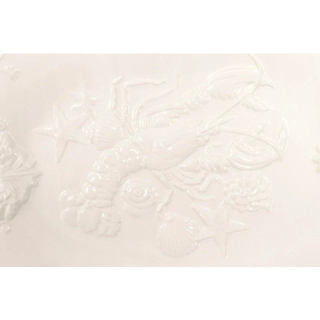 A white ceramic platter made by Sanor Ceramica of Portugal. Embossed with a coastal design, centered with a lobster amidst...