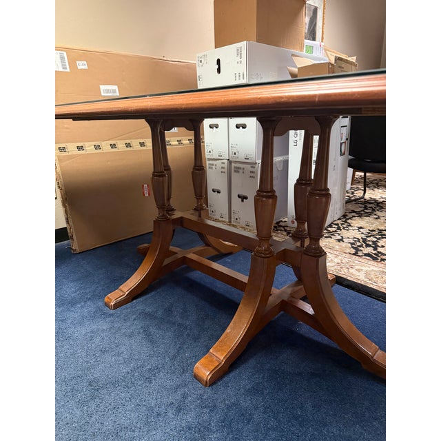 Sturdy wooden dining table with a rectangular glass top insert. This piece has a medium brown wood finish and a double...