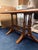 Sturdy wooden dining table with a rectangular glass top insert. This piece has a medium brown wood finish and a double...
