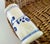 A distinctive vintage woven wicker basket featuring a broad oval form and a pair of blue-and-white porcelain handles. The...