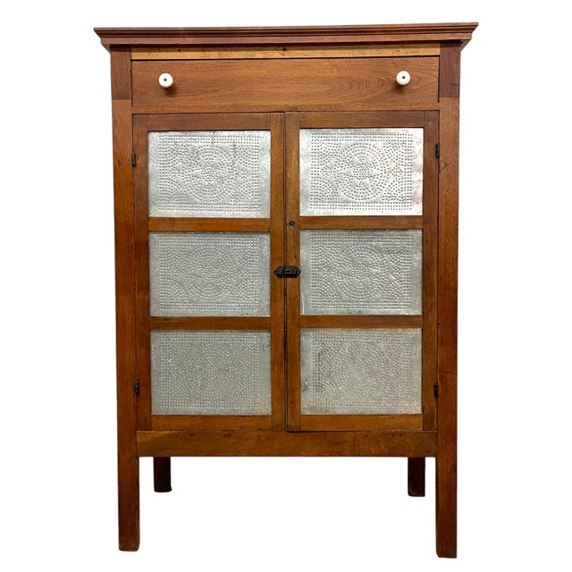 This antique-style pie cabinet is crafted from wood and features a classic, vertically oriented form with a double front...