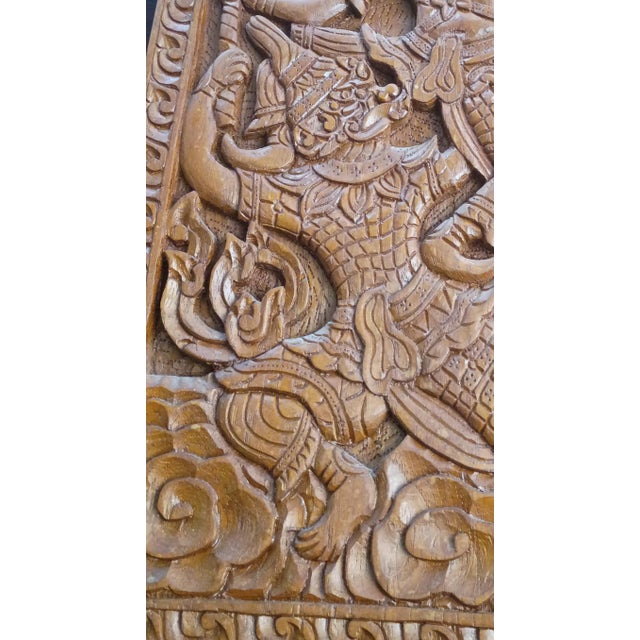 Intricately carved solid teak wood wall panel depicting a dramatic scene from the Ramakien, the Thai version of the...